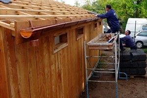 Sur la toiture, pose des gouttières et du lattage